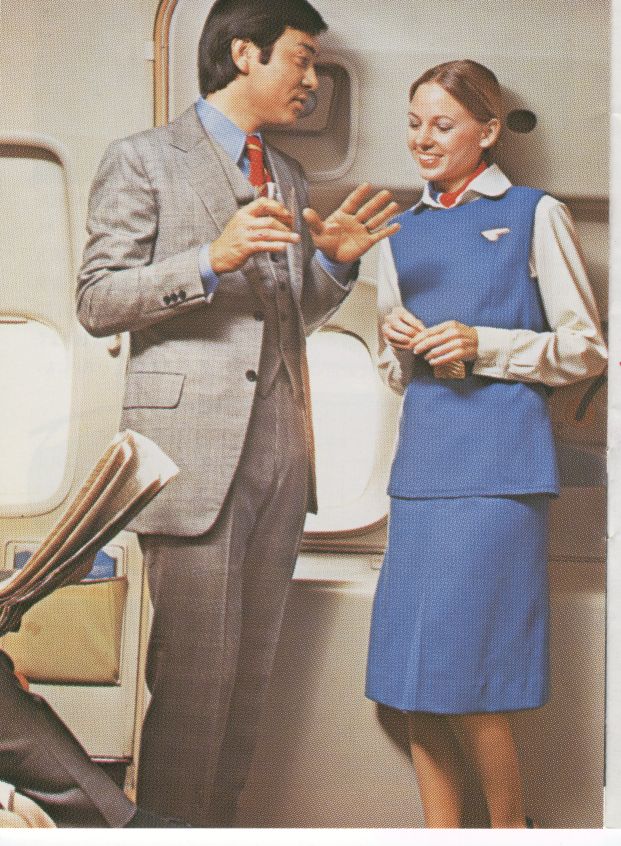 1976 A flight attendant speaking with a customer in the foyer of a 747 doorway.